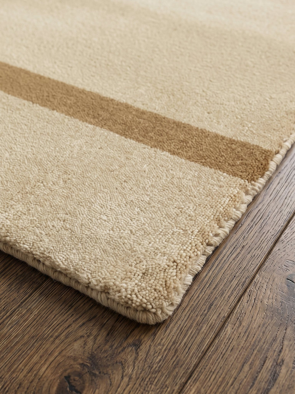 Corner of the Article 222 sand banded border merino wool hand-loomed rug showing the pile and finished edge