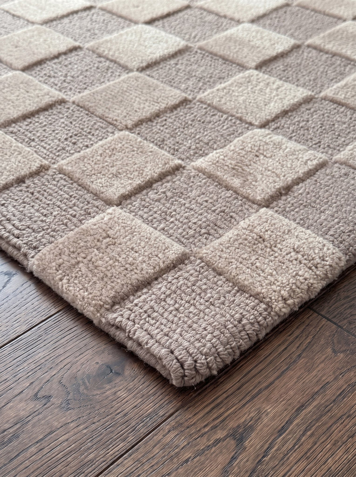 Corner of the Article 241 taupe checkerboard merino wool and cashmere hand-knotted rug showing the pile and finished edge