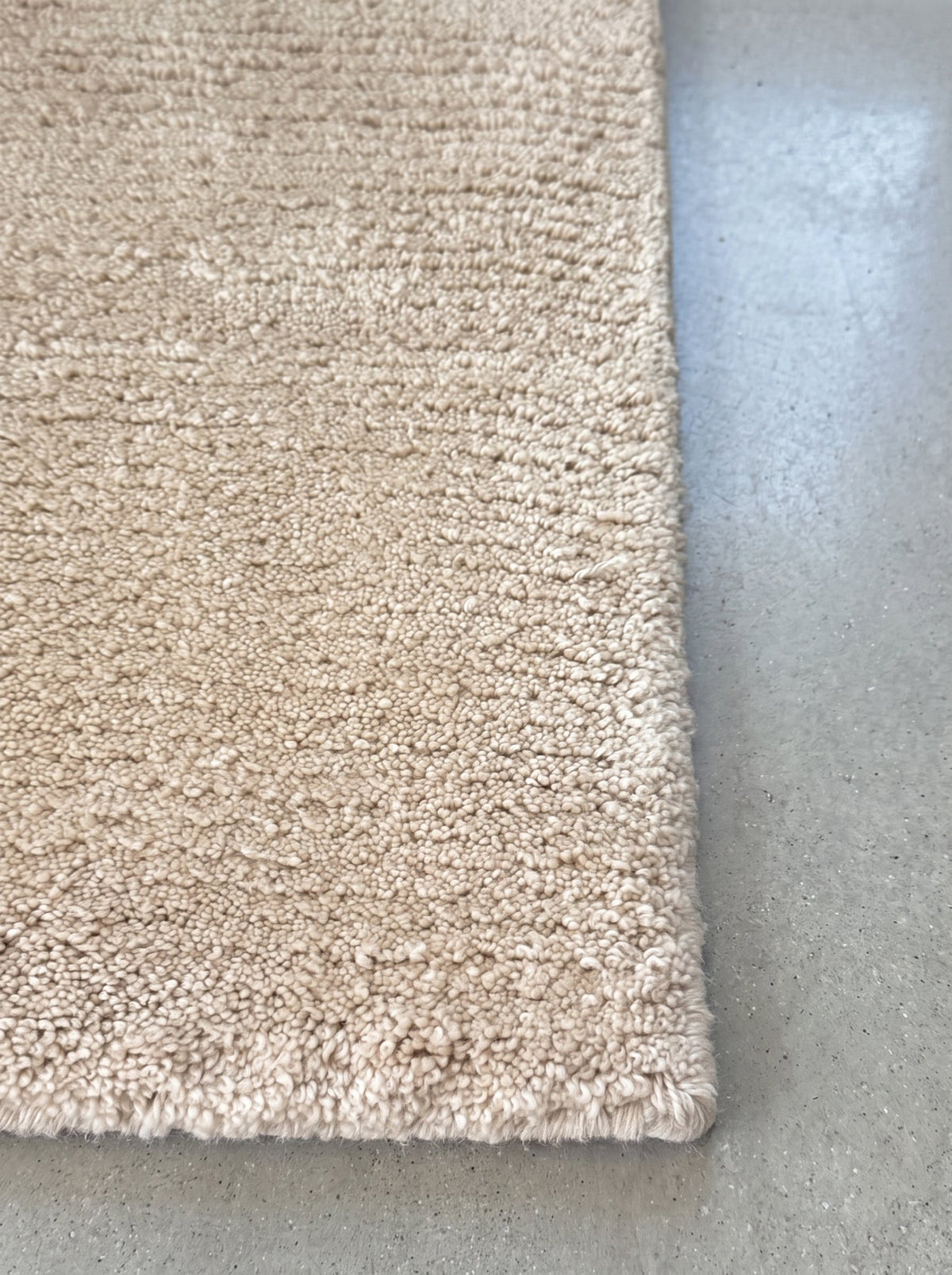 Corner of the Article 611 ivory solid cashmere handwoven rug showing the pile and finished edge