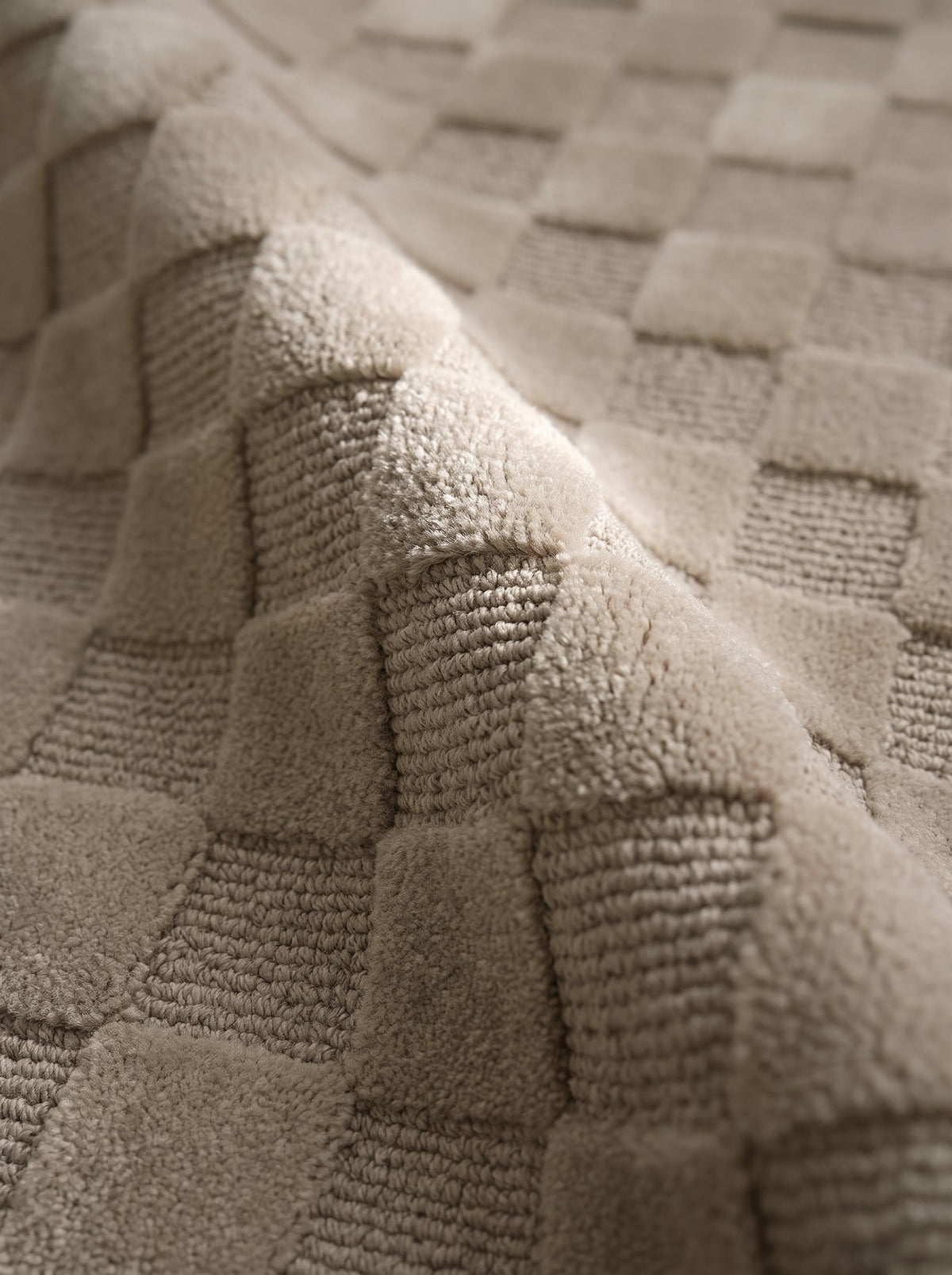 Article 241 taupe checkerboard merino wool and cashmere hand-knotted rug folded back to show pile depth and texture