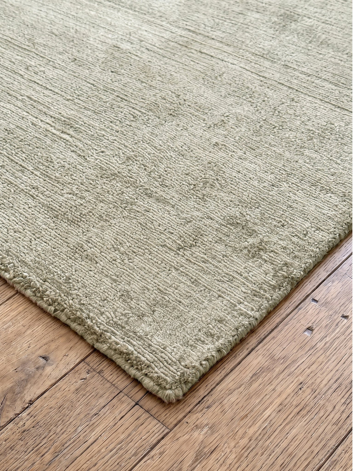 Corner of the Article 522 sage distressed silk hand-loomed rug showing the pile and finished edge