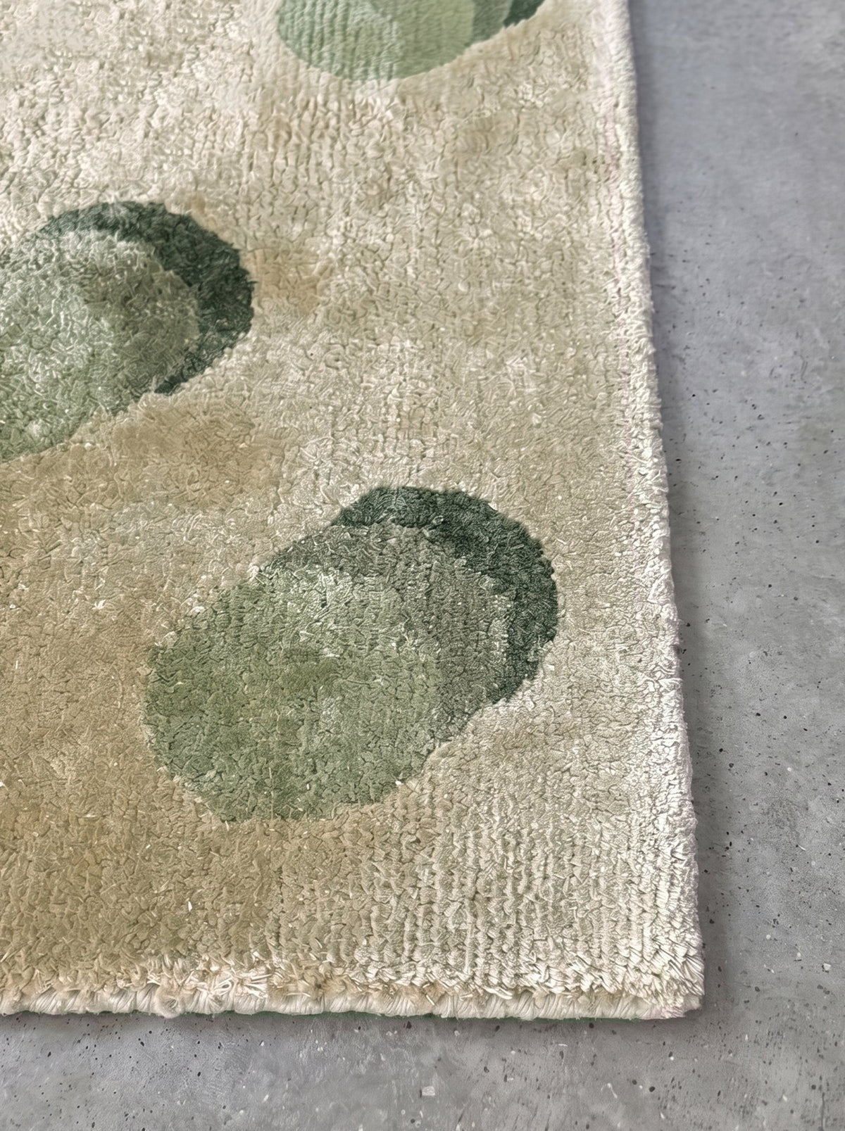 Corner of the Article 542 sage dot silk hand-knotted rug showing the pile and finished edge